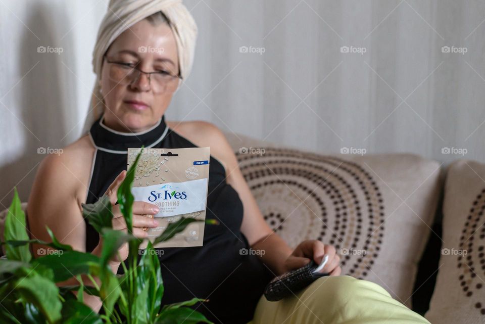 Aged woman with a cosmetics product in her hands, face mask brand St. Ives. Personal care