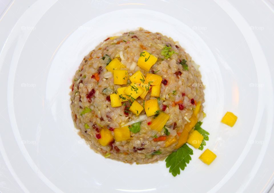 Integral rice with mango and vegetables on a white plate