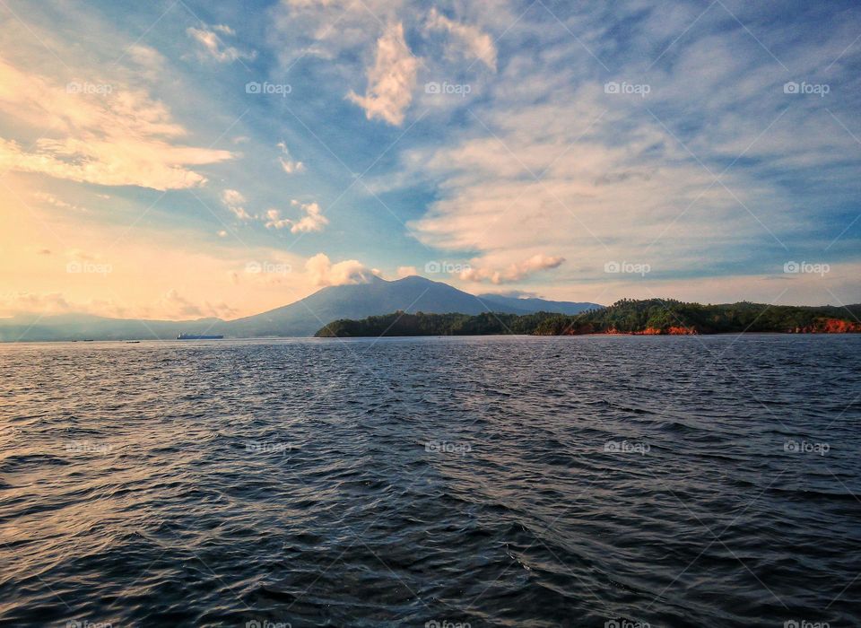 Natural scenery, view of the tip of the island against the backdrop of mountains and beautiful cloud formations.