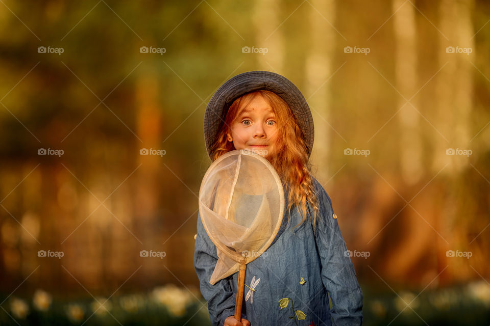 Little girl with butterfly net outdoor at sunset