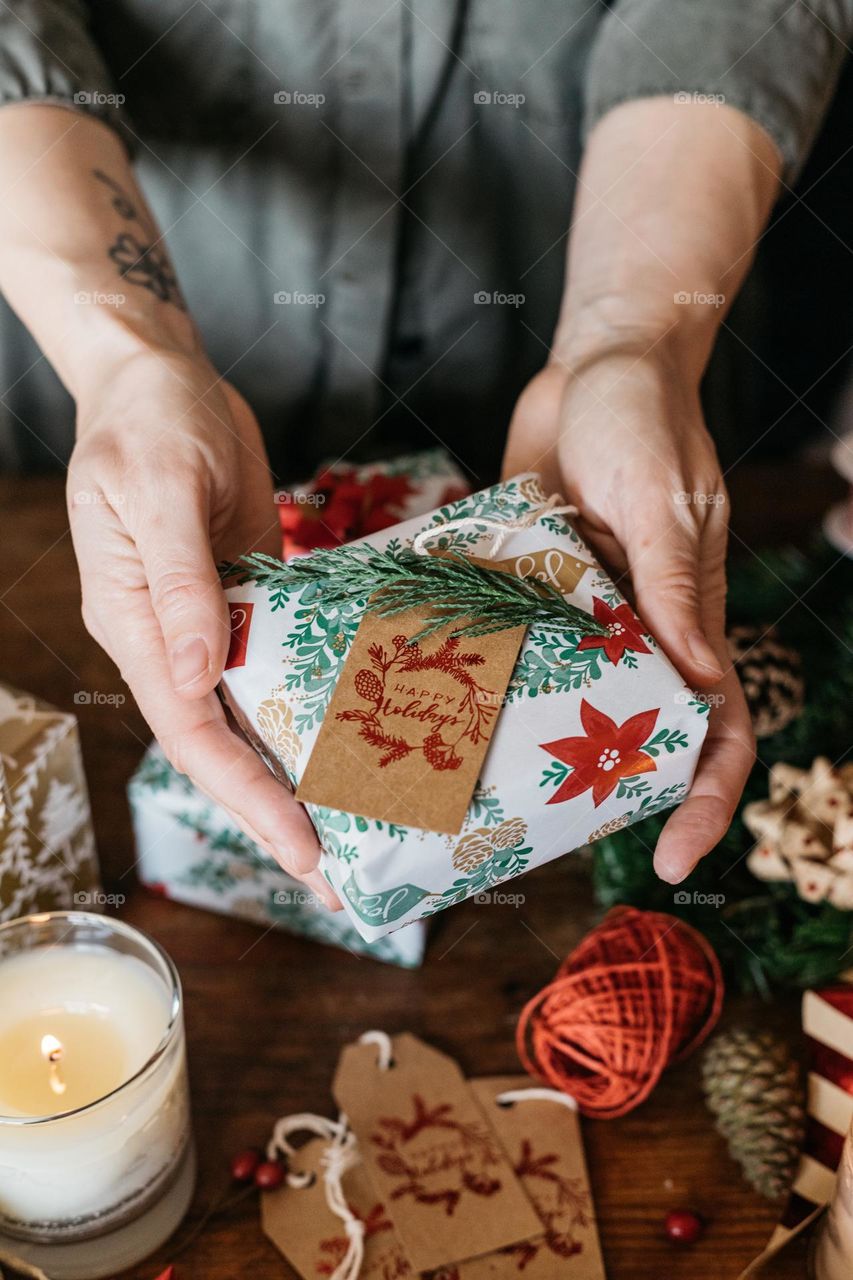 Woman holding a beautifully wrapped gift in her hands, while preparing for the Christmas holidays.