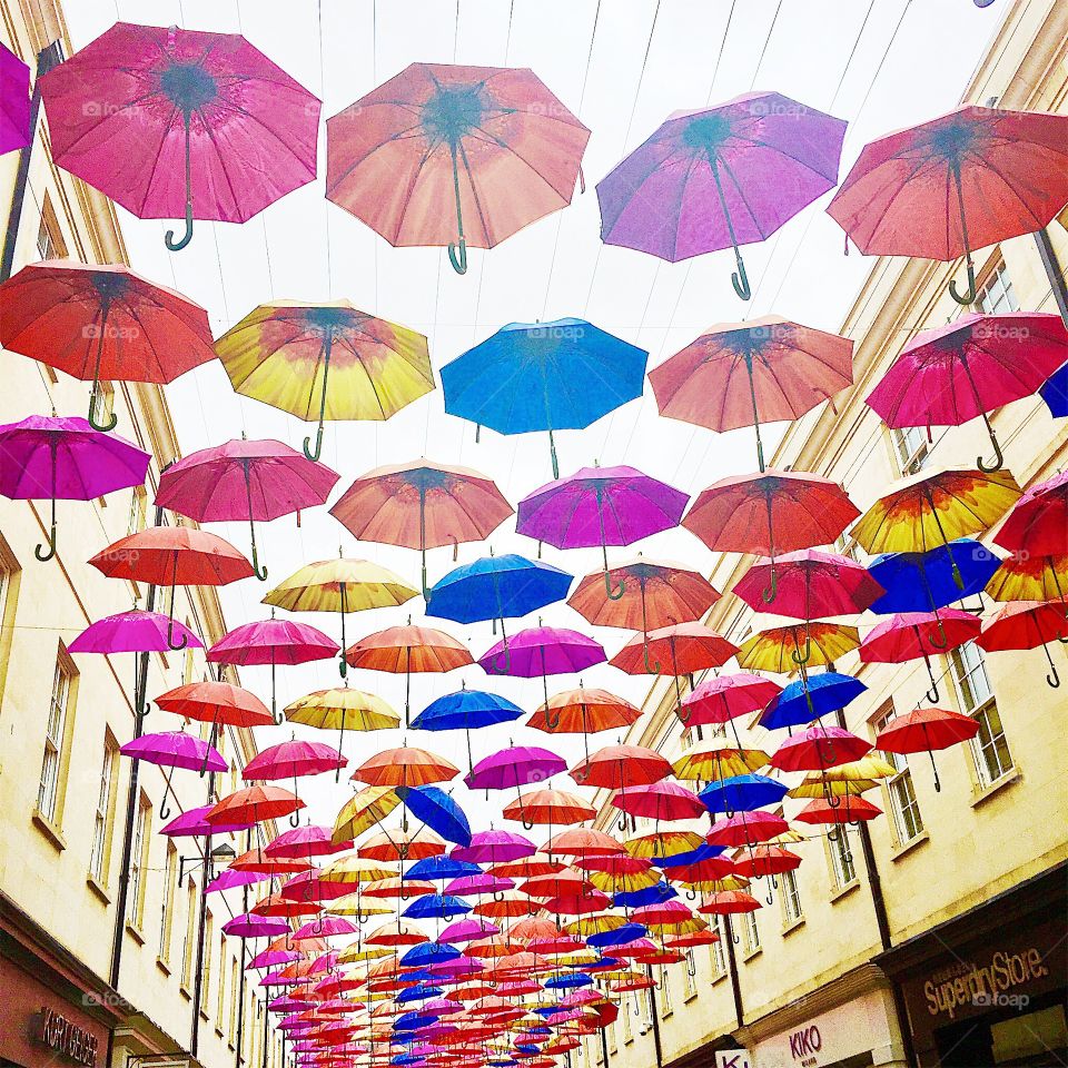 Skylight decor in the city of Bath in the UK for a festival. Colorful umbrellas strung above the street. 