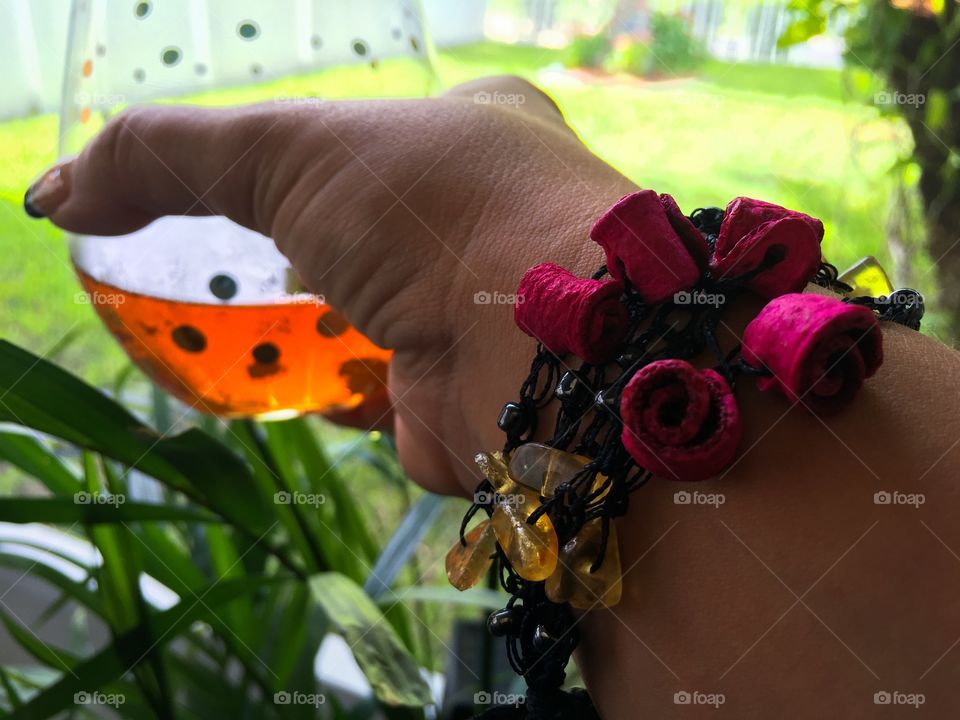 Bracelet on wrist, glass in hand 