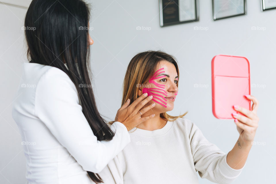 Young woman gets facial tape massage in spa beauty salon 