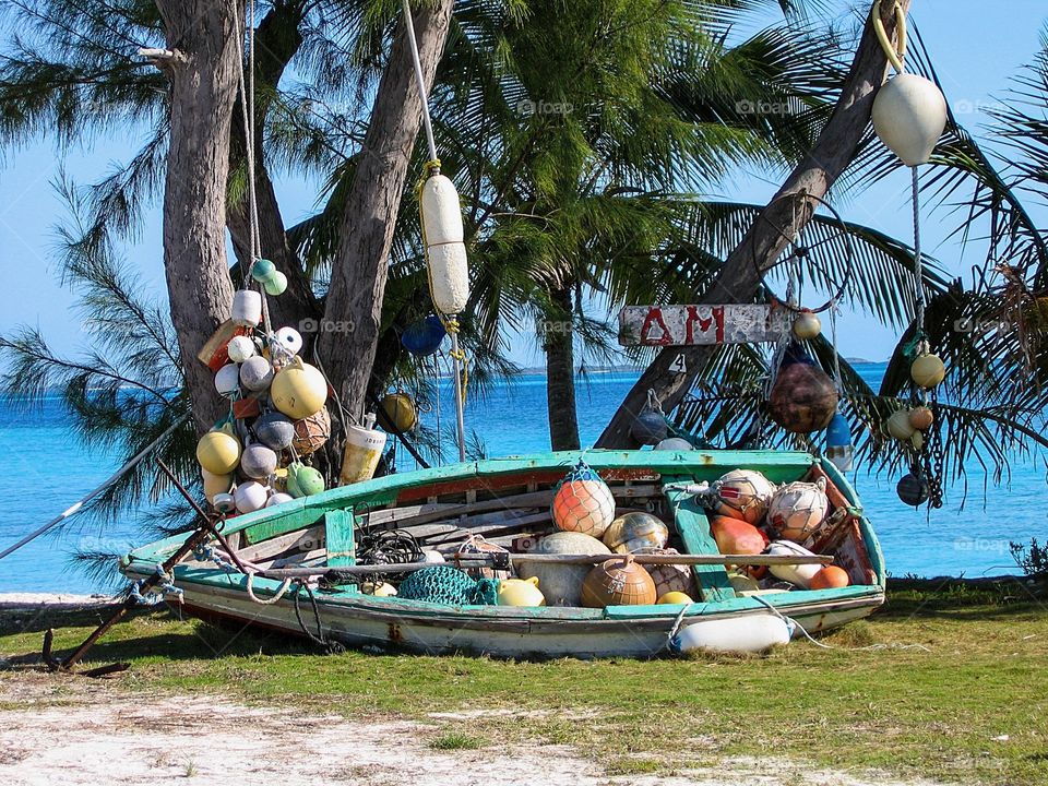 Rustic wooden boat with buoys and palm trees blue ocean photographed in the Exuma‘s in the Bahamas