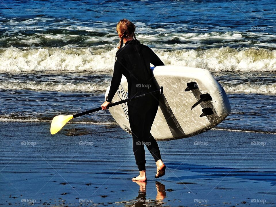 Woman entering the surf with her board in Pacifica, California