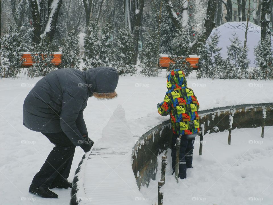 a man with a child makes a snowman