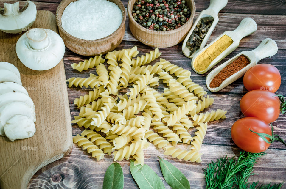 Raw pasta with ingredients and wooden accessories