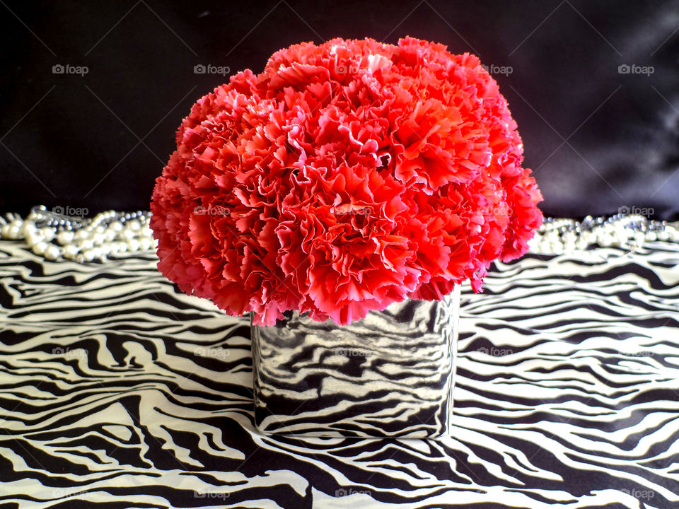 Pink carnations bouquet in a silver vase on animal print and black background 