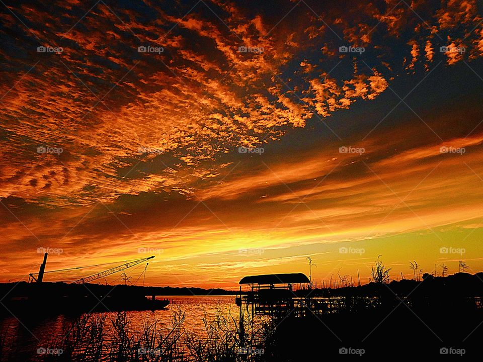 Magnificent rolling clouds converge on a descending sunset over the calm bay water