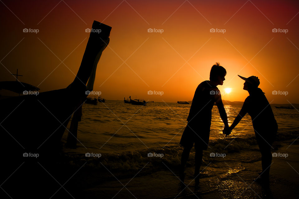 Couple standing on beach during sunset