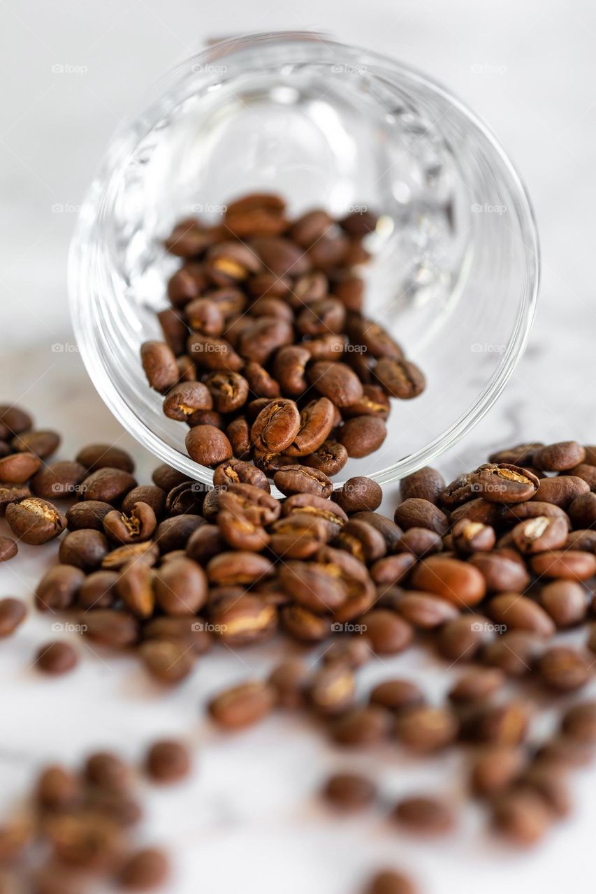 Roasted coffee beans spilled out of glass cup