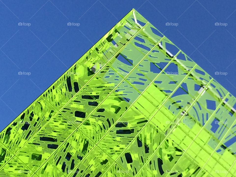 Lime Green Triangle Structure . Looking up at metal building against blue sky 