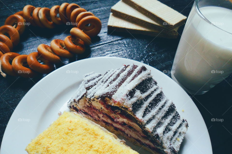 cakes, a cup of milk, bagels and waffles on a black background