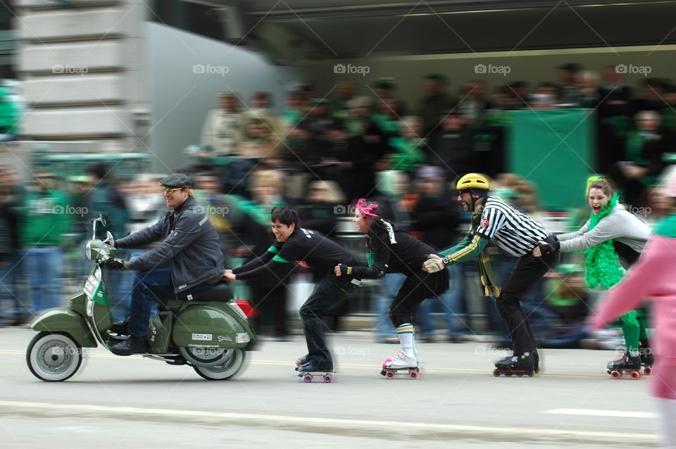 Group hitching a ride on a scooter in the St. Patrick's day parade in Cleveland, Ohio
