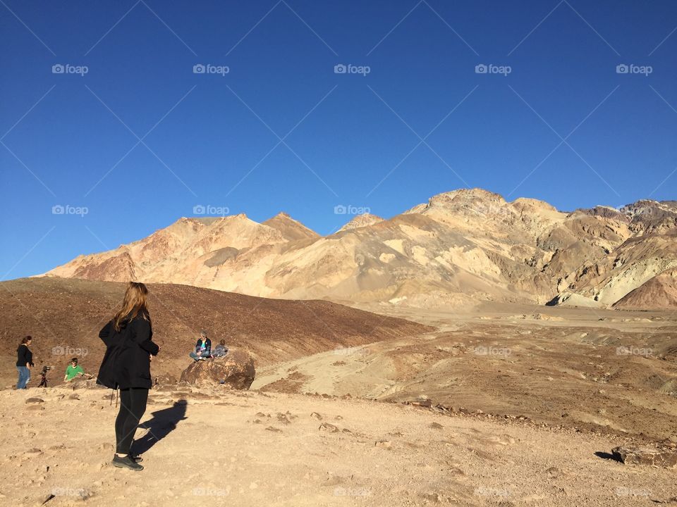 Tourists admiring a golden desert hill formed due to volcanic activity and oxidation