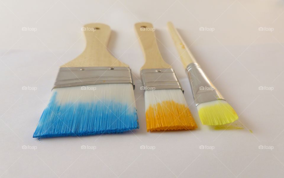 Paint brushes with paint yellow orange blue