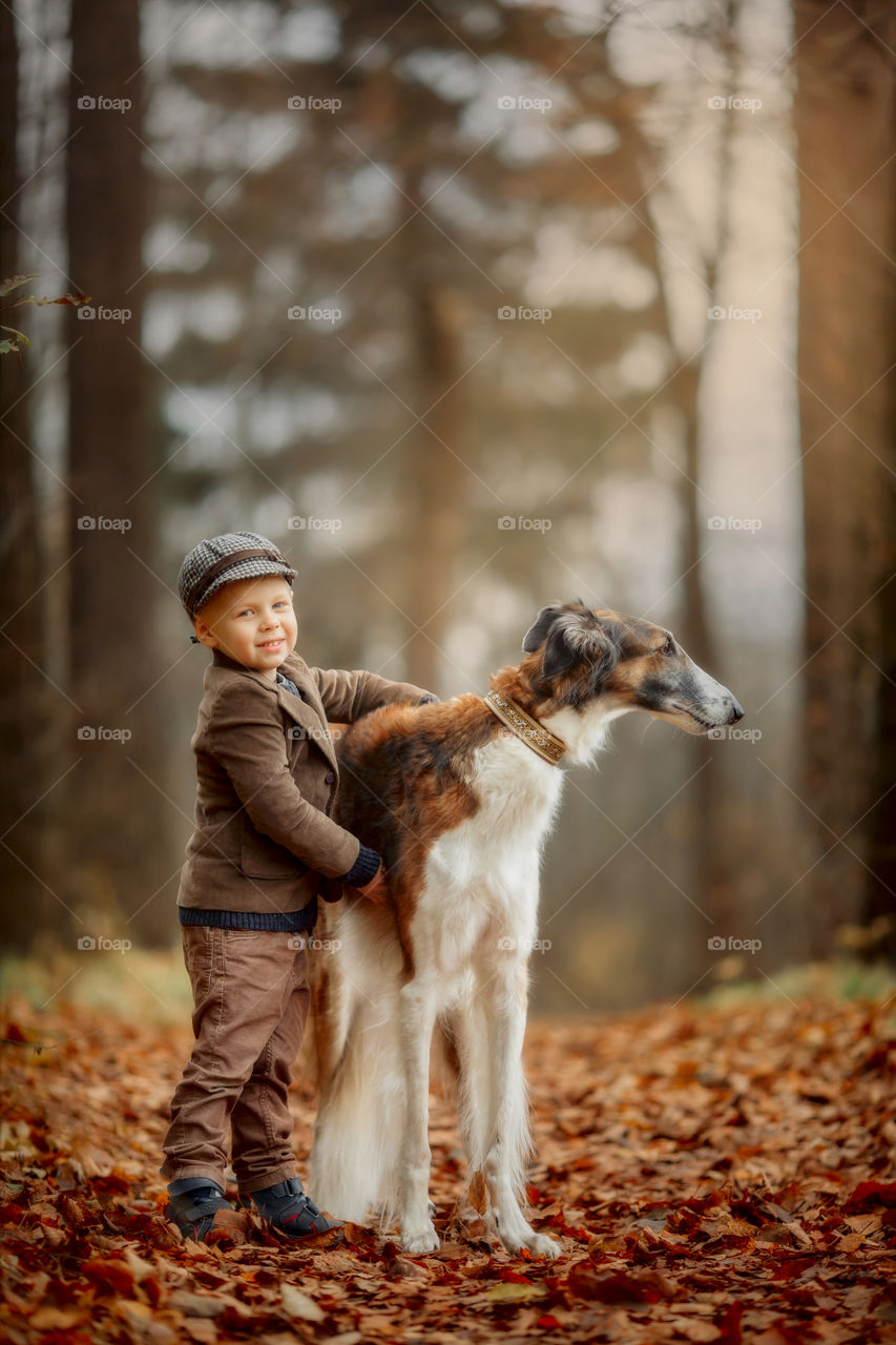 Cute boy with russian borzoi dog in an autumn park 