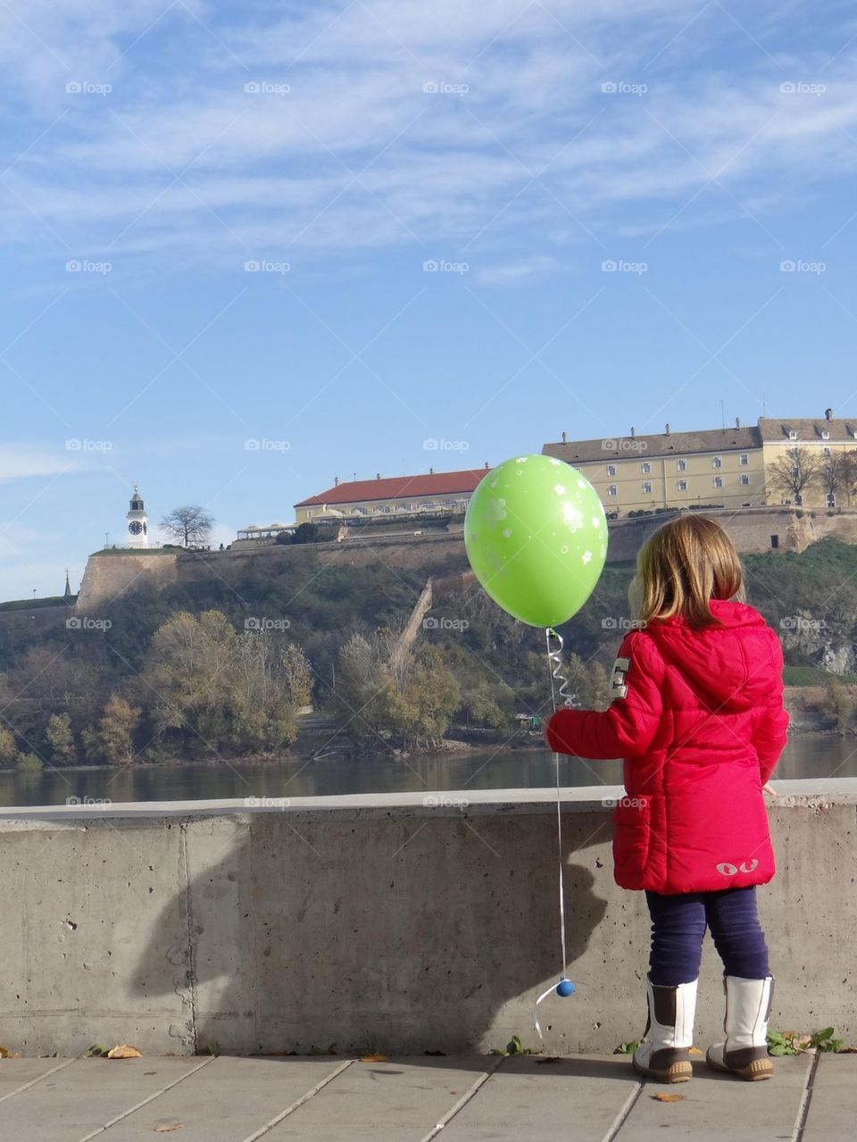 little girl in red jacket with green baloon