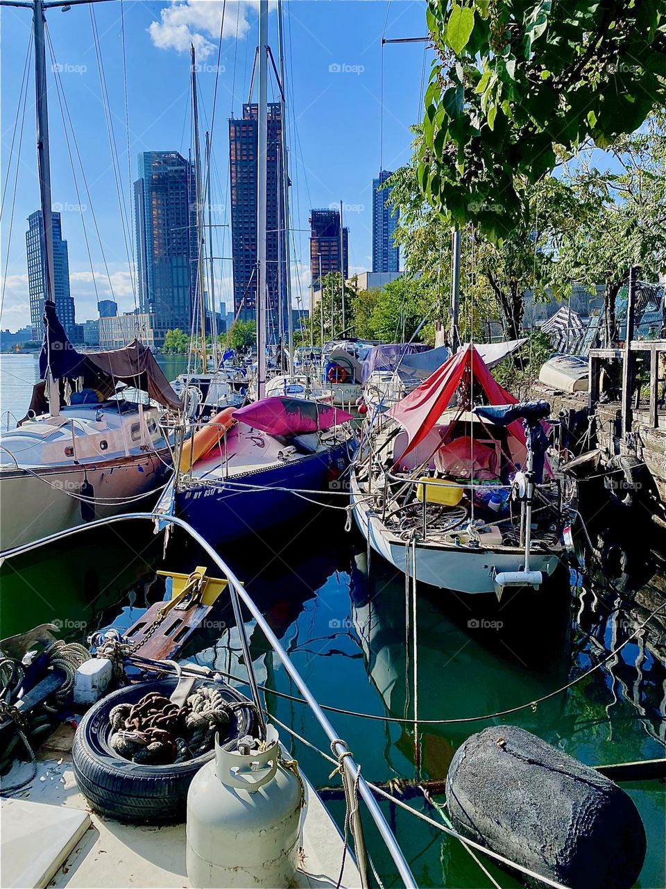 These boats are all tied to the shore at „Newtown Creek“ by the „Pulaski Bridge“ In LIC, Queens onto a tree lined strip of land that amongst other things houses a handcrafted wooden veranda where parties are sometimes held. 2023. Hypnotic Productions