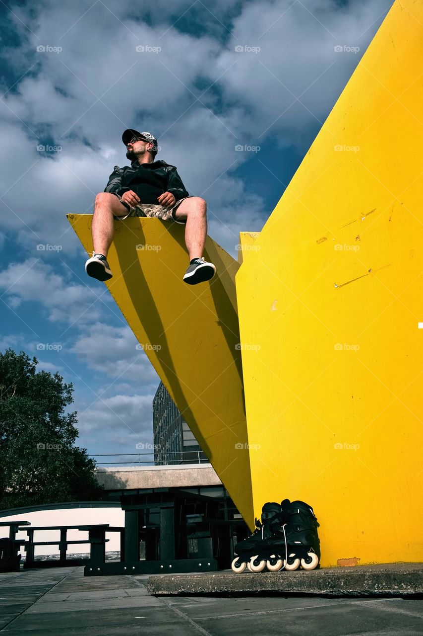 Bearded man with glasses sitting high on yellow statue