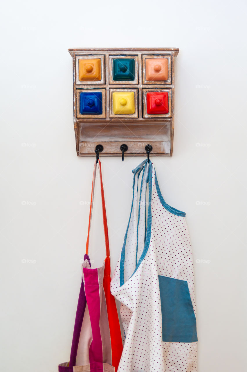 Kitchen aprons and colorful chest of drawers.