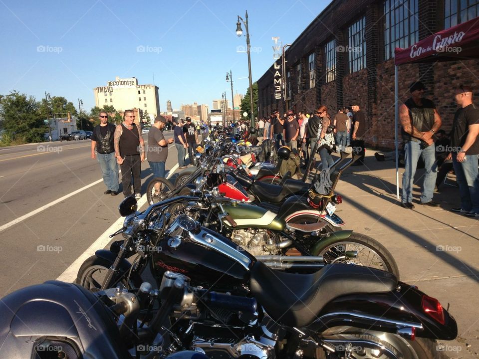 Another view of bikes lined up and bikers viewing them