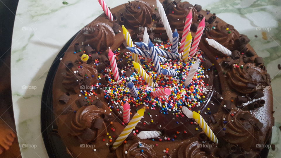 Birthday cake, decorated by a toddler with sprinkles and candles