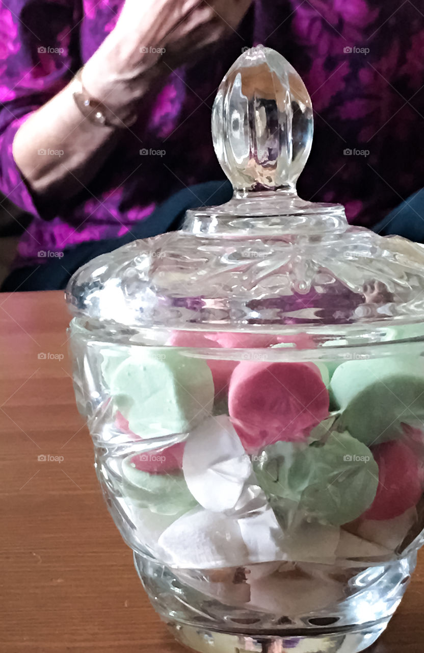 Crystal bowl full of mint candies, closeup with person blurred in background 