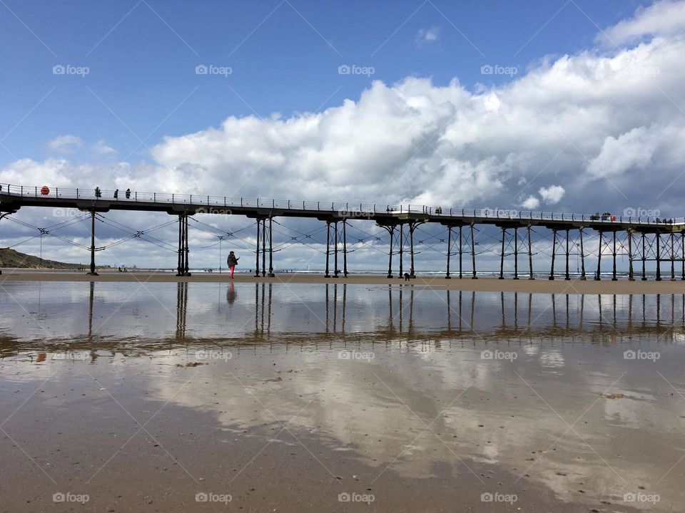 Landscape …Saltburn  Pier with blue sky above and a reflection in the wet sand below 