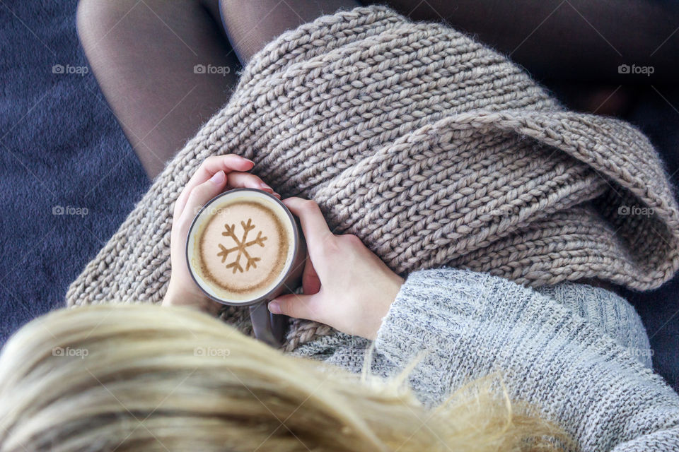 Girl with a cup of coffee resting on a bed in the room