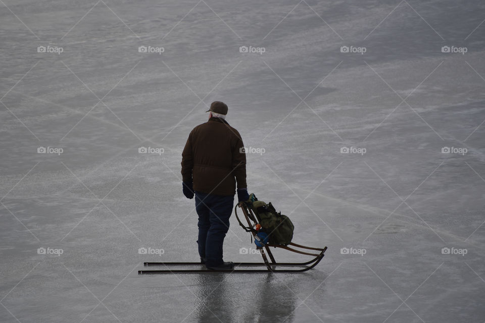 Old man with sledge over a frozen lake, Kolmården, Sweden 