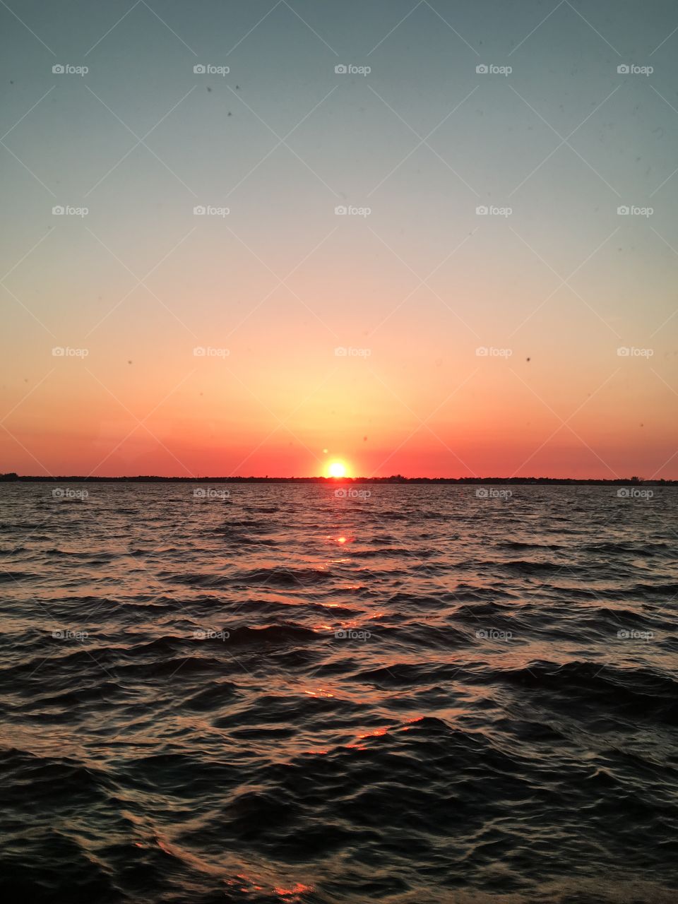 A photo of the Sunset reflected upon the water of the ocean.