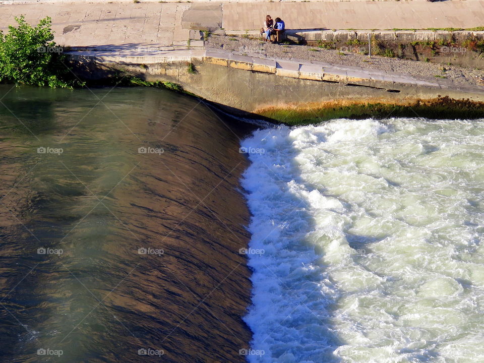 couple sitting on the river with rapids bank