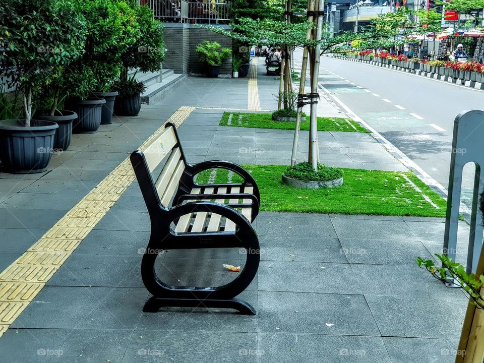 Sidewalk benches in front of the shopping center buliding, city street sidewalk benches, city of Bandung Indonesia, Around ornamental plant of green leaves flowers in pots, and plantes on the sidewalk add to beauty shopping area