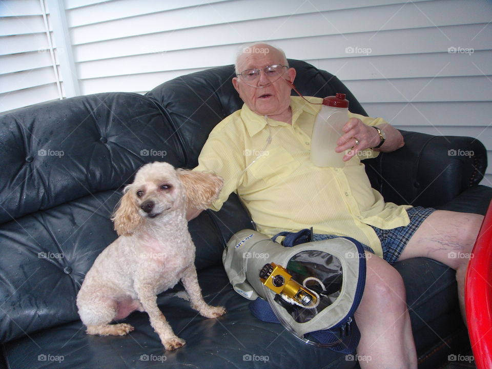 Sick senior man with supplemental oxygen sitting with dog