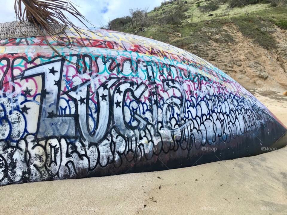 Lonely graffiti boat on the beach