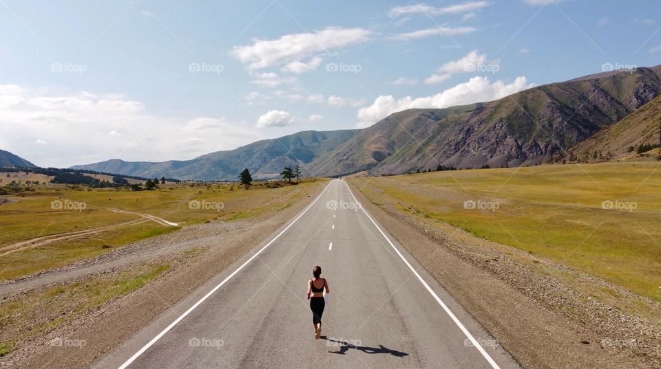 Young woman is running on an empty road 