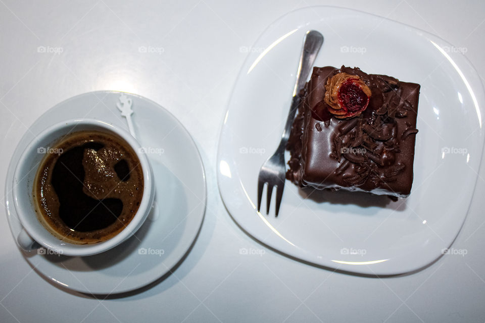 Chocolate mousse with raspberries on a white plate and a black coffee cup