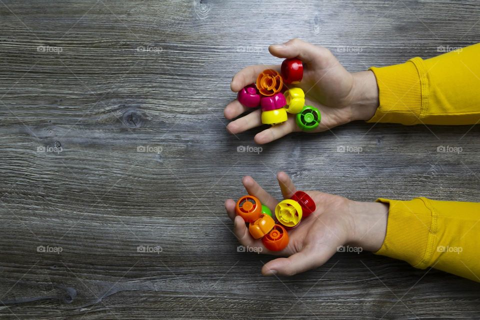 We collect garbage, plastic plugs and plastic to save our planet, nature and the environment. Men's hands lie on a gray wooden surface, which is used as a background or a surface with incident light.