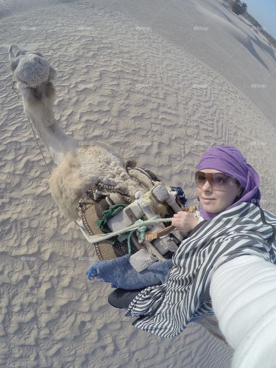 Girl riding a camel in the Sahara desert and taking a selfie