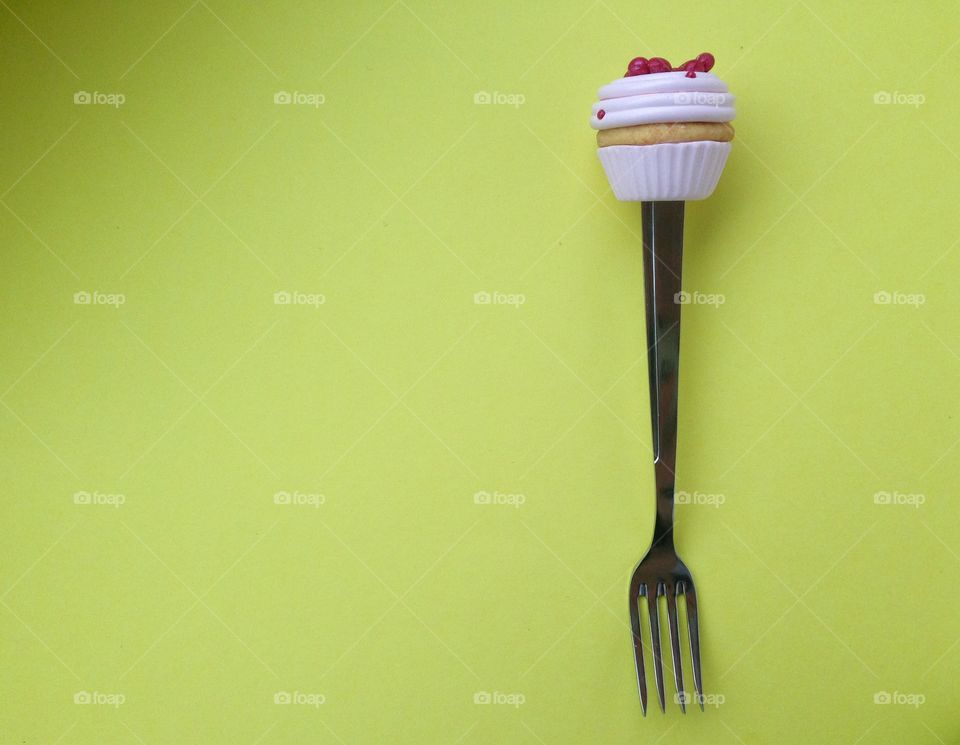 Fork with cupcake on top on yellow back

