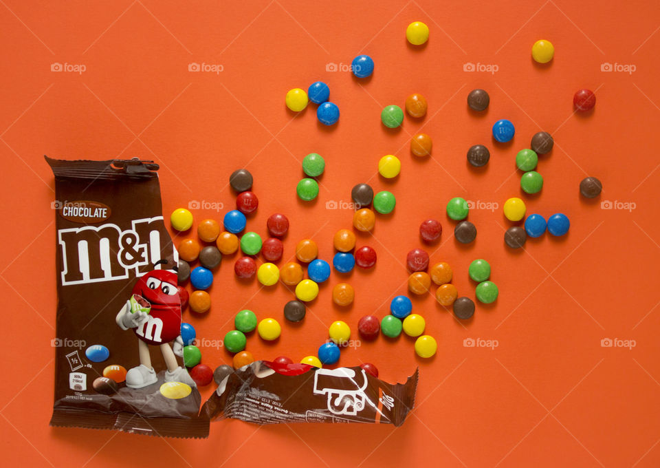 Sweet colorful candies on the orange colored background