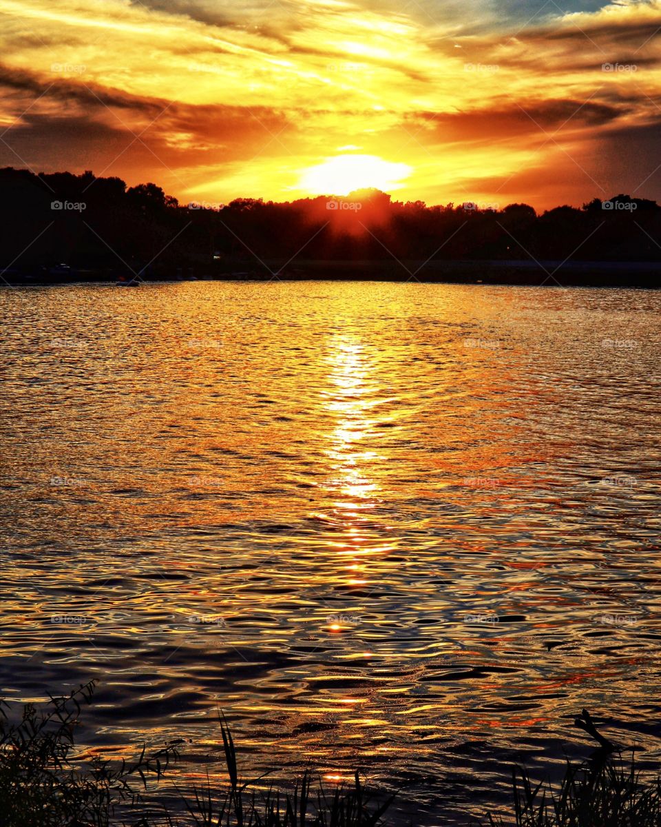 A sunset down by the lake in Indiana on a summer day with a beautiful sky and beautiful water 