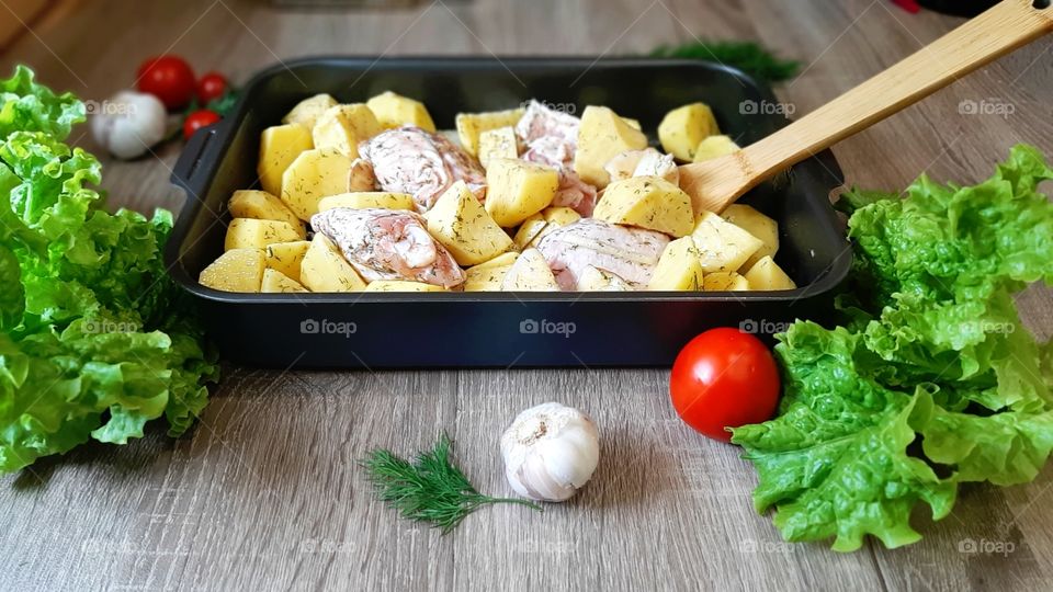 Potatoes with chicken in garlic before baking.