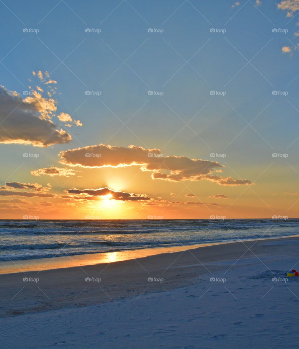 Magnificent sunset -  I watched with an unwavering gaze, as a fiery orange orb of light slowly sank beneath the horizon, and threads of light lingered in the sky, 
mingling with the clouds