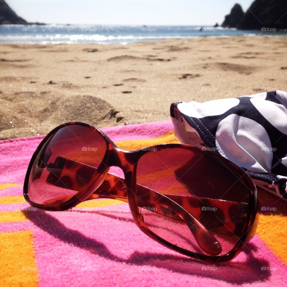 Sunglasses on a beach. Sunglasses on beach towel on a sandy beach
