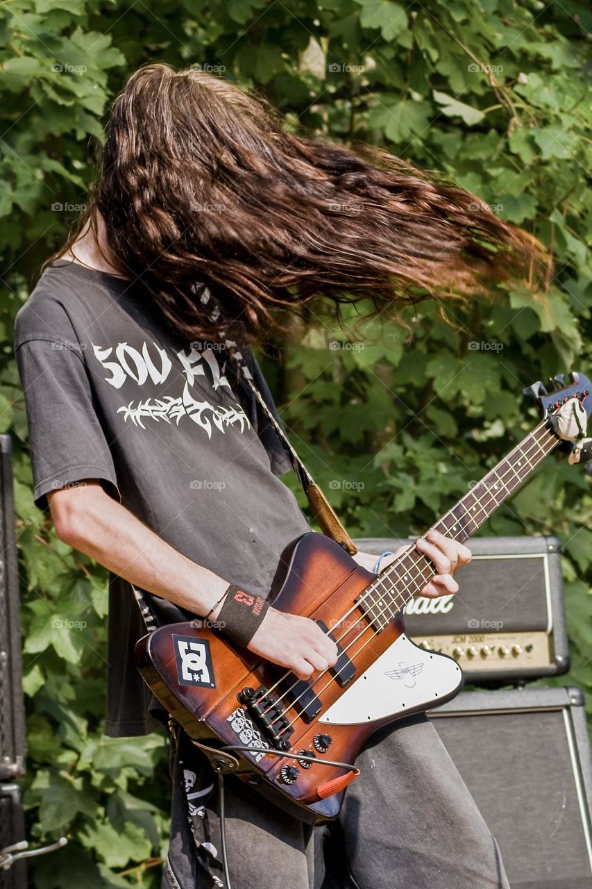 Bass player rocking out with lots of hair at an outdoor festival