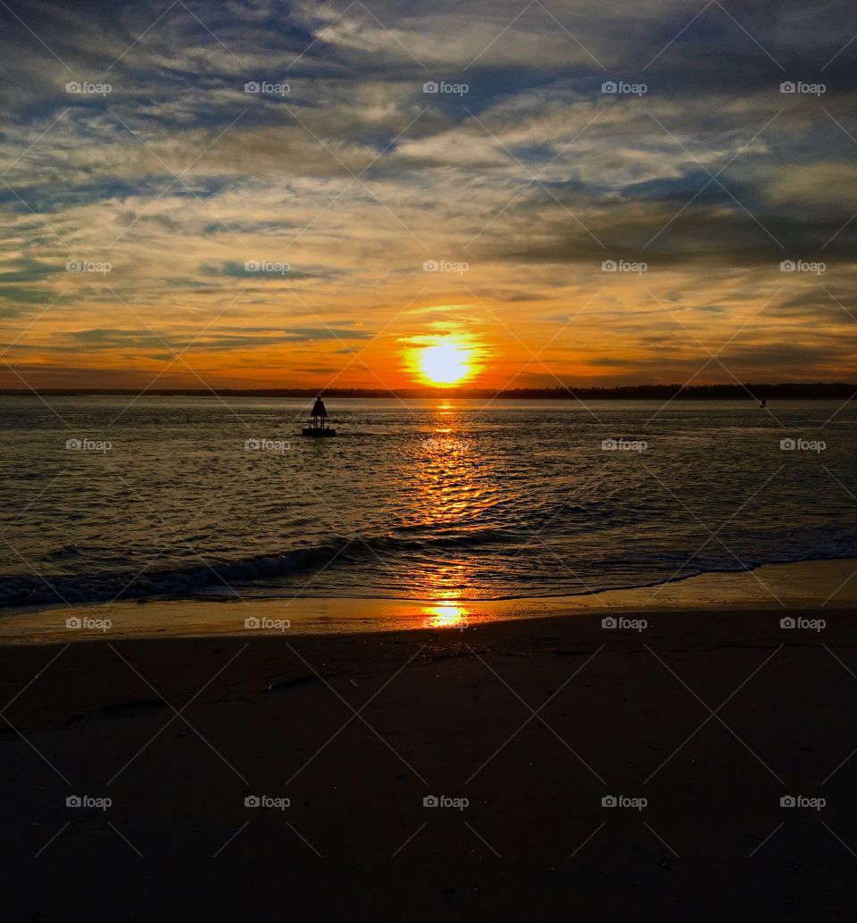 The glowing sunset begins to fall below the horizon casting its luminous reflection upon the sea. 