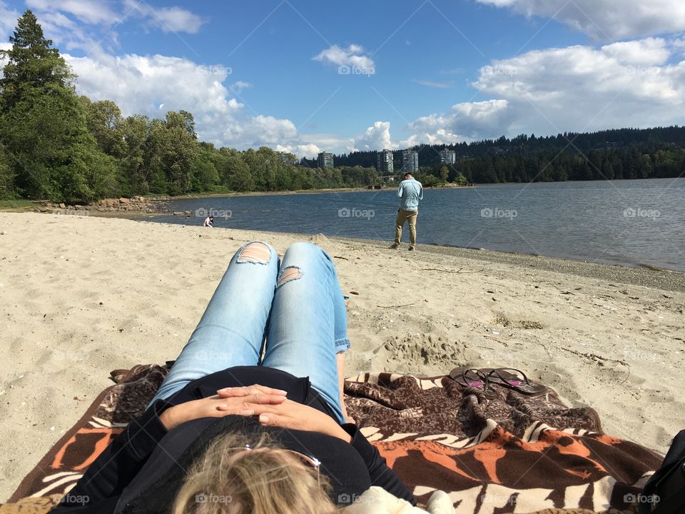 Woman relaxing, lying down o. Blanket  on shore of alpine lake o. The Canadian Rocky Mountains 